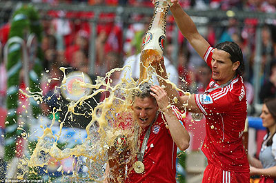Bayern midfielder Bastian Schweinsteiger is drenched in beer by team-mate Daniel van Buyten as they celebrated winning the German league. Net photo.
