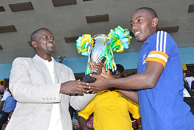 The Ministry of Sport's Permanent Secretary Edward Kalisa presents the second division league title to Esperance Fc captain on Sunday after the climax of the lower division season.