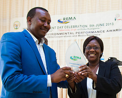 Leandre Karekezi (L), the mayor of Gisagara, receives an award his district won for protecting the environment from State Minister for Social Affairs, Dr Alvera Mukabaramba, yesterday. The New Times / Timothy Kisambira