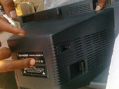 RBS officials show a fake Sharp label on one of the impounded TV sets.  The New Times / Peterson Tumwebaze