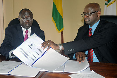 Karugarama (L) and Busingye sign documents during the  handover ceremony yesterday. New Times,/John Mbanda. 