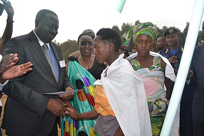 DR Congo minister of Internal Affairs Mangeze gives a birth certificate to a mother at Kigeme refugee camp yesterday as minister Mukantabana looks on.   The New Times/ JP Bucyesenge 