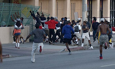 A group of people in Los Angeles attempt to tear down a fence after attending a prayer rally Monday to protest the verdict in the George Zimmerman trial. Net photo.