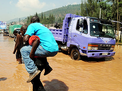 A man is carried across a flooded Nyabugogo highway after a downpour. Flooding will be minimal this rainy season. The New Times/File