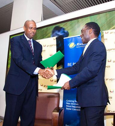 RwandAir CEO John Mirenge (left) and Cornwell Muleya, the Air Uganda boss, exchange documents after signing the deal. The New Times / Timothy Kisambira