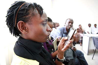 A lady reads a text message on her mobile handset. The New Times/ File.