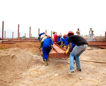 Workers carry metal frames at a construction site. The New Times/ T. Kisambira.