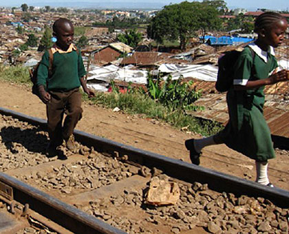 School children walk along a railway line in Kibera, a slum in Nairobi.   EAC leaders want the Mombasa-Kampala-Kigali railway line fast tracked.   The New Times/ Net Photo. 