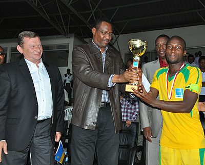 The Minister of Sports and Culture Protais Mitali giving the Super Cup trophy to AS Kigali captain Jimmy Mbaraga yesterday. Looking on Babil Groupu2019s Head of International ....