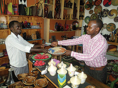 Konga serves a customer at his crafts shop in Kigali city. The New Times / Ivan Ngoboka
