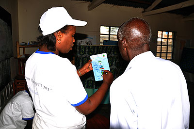 A returning officer guides an elderly man at polling station in Kigali. The New Times/John Mbanda.