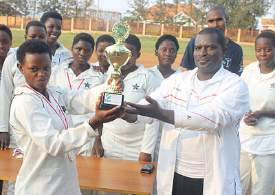 Emmanuel Bugingo, the Director Sports in the Sports ministry hands over the trophy to IPRC captain Josu00e9e Marie Muhoza. The New Times / Courtesy.