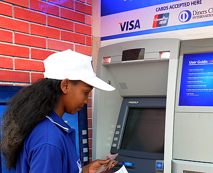 A bank client transacts from an ATM booth in Kigali. Cards are replacing papers. The New Times/ File.