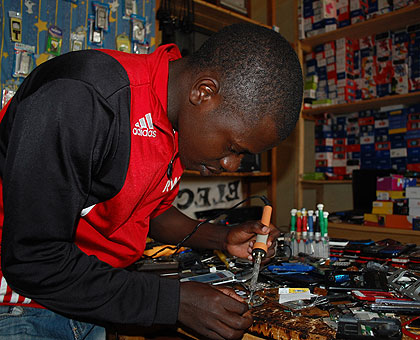 Kwizera repairs a phone in his shop located in Nyamagabe town. The New Times/Jean-Pierre Bucyensenge