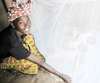 A mother lays mosquito nets over begging for children to sleep in. Scientists are closer to using malaria vaccine. Net photos.