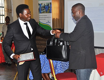 MP Bamporiki (L)recognises one of the best performers with a  certificate and laptop.   The New Times/ Susan Babijja. 