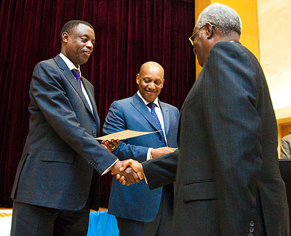 Defence minister James Kabarebe (L) hands over a certificate to General (Rtd) Marcel Gatsinzi as Chief of Defence Staff, Gen. Patrick Nyamvumba looks on.Saturday Times/ Timothy Kisambira.  