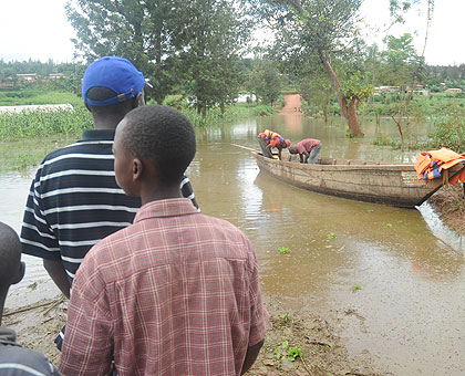 Passengers wait for a canoe to cross a road to Masaka, Kicukiro District  after a heavy downpour in the past. An outpouring of rain has been experienced across the country since last week. The New Times/ File. 