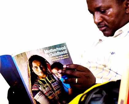 A participant reads the UNFPAu2019s State of World Population 2013 report yesterday. The New Times/ Timothy Kisambira.