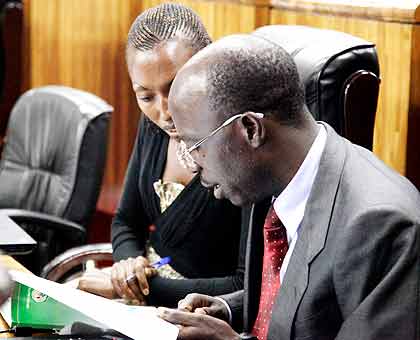 MPs Manirora Annoncee (L) and Theobald Mporanyi scrutinise the Ombudsman report yesterday. The New Times/ John Mbanda.