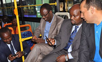 Nsengiyumva (second right) and City of Kigali Mayor Fidel Ndayisaba enjoy free Internet on a city commuter bus during the launch of the u2018Smart Kigaliu2019 initiative. The New Times / File 