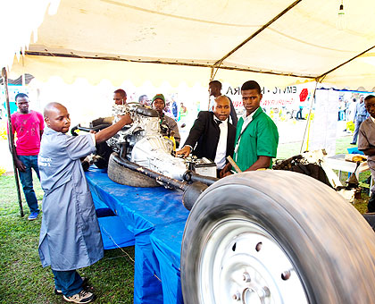 Jean Damascene Ahabagihirwe (L), from VCT Expert Motors, Remera, demonstrates how the car engine system works at the ongoing  TVET expo yesterday. The New Times/ Timothy Kisambira.