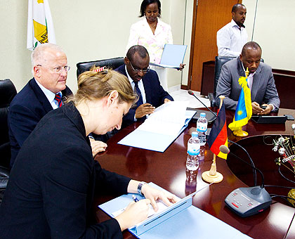 Dr Beckmann (foreground) and Amb. Gatete (C) sign the deal as Fahrenholtz looks on. The New Times/ Timothy Kisambira.