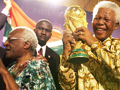 Nelson Mandela lifts the World Cup Trophy after playing a crucial role in winning South Africa the rights to host the 2010 finals. Left is his anti-Apartheid struggle colleague archbishop Desmond Tutu. Net photo.