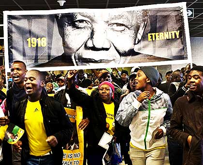 South Africans approach FNB Stadium in Soweto with a banner of Nelson Mandela yesterday. Over 50,000 people braved the rain to honour the  departed anti-apartheid hero at the historical stadium of his first public speech after release from jail in 1990, and last public appearance in July 2010. Net photo.