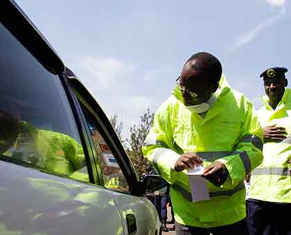 Ndayisaba explains to a driver the meaning of a road safety sticker before placing it on his car. The New Times/ T.Kisambira.