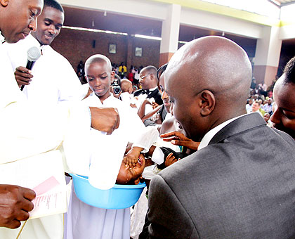Father Andrew Baributsa (L) baptises a child at Saint Michel Cathedral in Kigali on Christmas Day. The New Times/Timothy Kisambira
