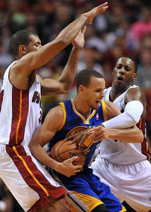 Golden State Warriors point guard Stephen Curry (C) is fouled by Miami Heat point guard Mario Chalmers (R) as small forward Shane Battier (L) defends the play during the second hal....