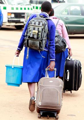 Students drag their heavy bags in the taxi park. Education Times / T. Kisambira