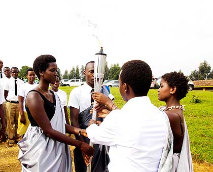Pascaline Niyigena (2ndR) and Adolphe Gahima (R) hand over the Flame to Taise Uwishema (centre-left) and Pacide  Umuhire, students of Nyange SS  at the school. The New Times/ Timothy Kisambira.