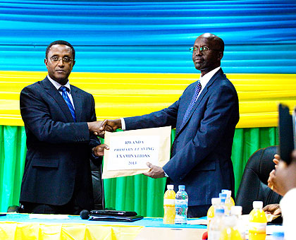 Dr Biruta (L) receives an envelope containing results from Dr John Rutayisire, the director-general of Rwanda Education Board, at the Board offices in Remera, Kigali, yesterday. The New Times/ Timothy Kisambira.