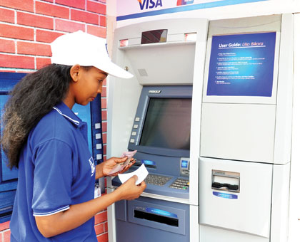 A lady withdrawing money from an ATM machine.  The New Times/ Timothy Kisambira.