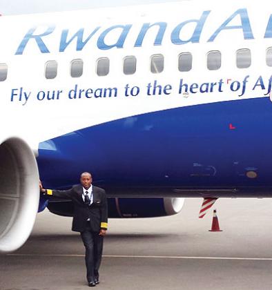Murabukirwa stands next to a RwandAir plane. He became the first Rwandan national pilot to put on a four- striped pilot jacket.