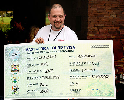 A tourist shows off a dummy East African Tourist Visa at the Heads of State summit in Kampala, yesterday. Courtesy.