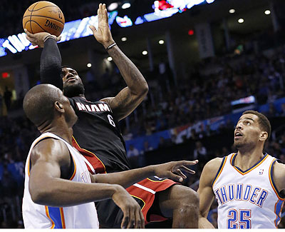 Miami Heat forward LeBron James (6) shoots between Oklahoma City Thunder forward Serge Ibaka (9) and guard Thabo Sefolosha (25) during the second quarter.