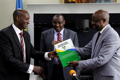 Ben Kagarama (R) gives a book containing Rwandau2019s fiscal laws and regulations to new RRA boss Richard Tusabe as Minister Gatete looks on during the handover yesterday. John Mbanda.