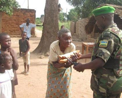 A Rwandan peacekeeper handing food to an old woman in Bangui. (Courtesy)