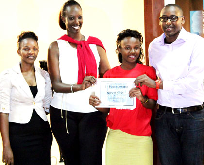 Sibo (second right) receives her certificate from Tigo staff. (John Mbanda)
