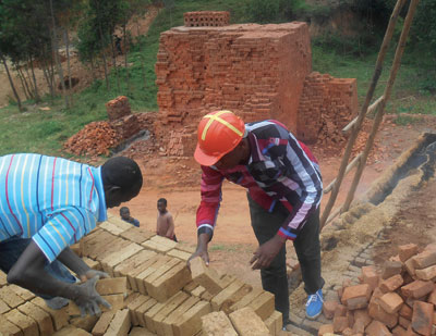 Francois (right) helps one of his workers prepare bricks for burning. The New Times / Peterson Tumwebaze.