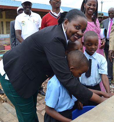 Eng. Isumbingabo with children open water in Shyorongi school as officials look on. J. Du2019Amour Mbonyinshuti.