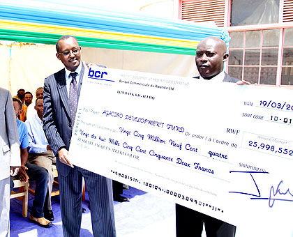 Kagabo and Ndamage hold a dummy cheque from Ameki Color. John 