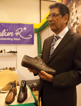 AD Santchurn, the MD of Manisa, displays shoes made by his firm during the exhibition. The New Times / Timothy Kisambira