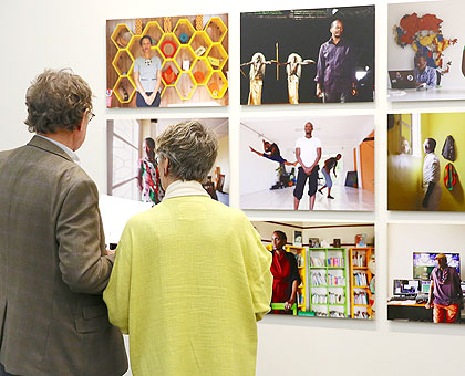 A curator takes a visitor at the exhibition through various pictures depicting lifestyle in Rwanda. (Courtesy)