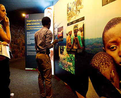 Visitors look at wall pictures at Kigali Genocide Memorial Centre in Gisozi depicting the impact of the Genocide. (Timothy Kisambira)