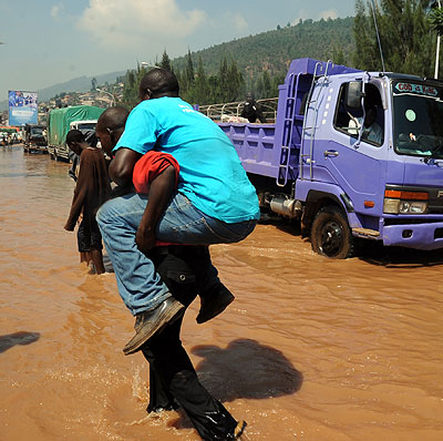 A man is carried across the flooded Nyabugogo highway after paying Rwf100.  File.