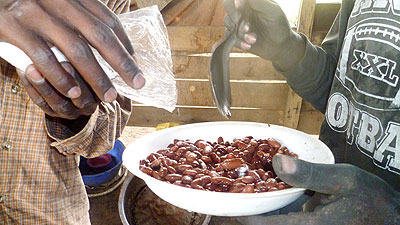 A man adds salt to a plate of fast-food beans popularly known as u2018M2Uu2019 that he shares with a colleague in Kigali.   Seraphine Habimana.